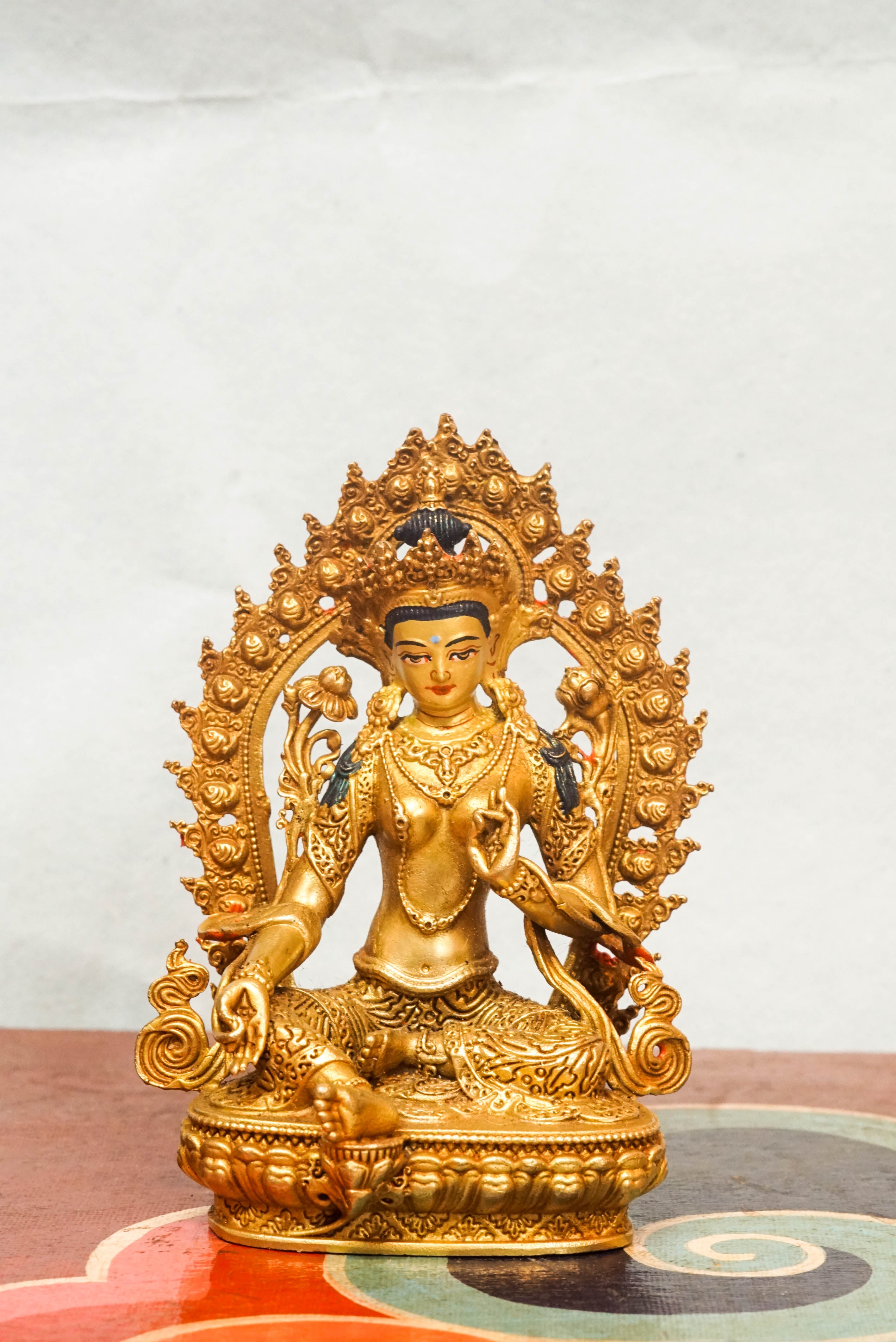 Gold-plated Green Tara statue with flaming halo, symbolizing compassion, protection, and spiritual transformation.