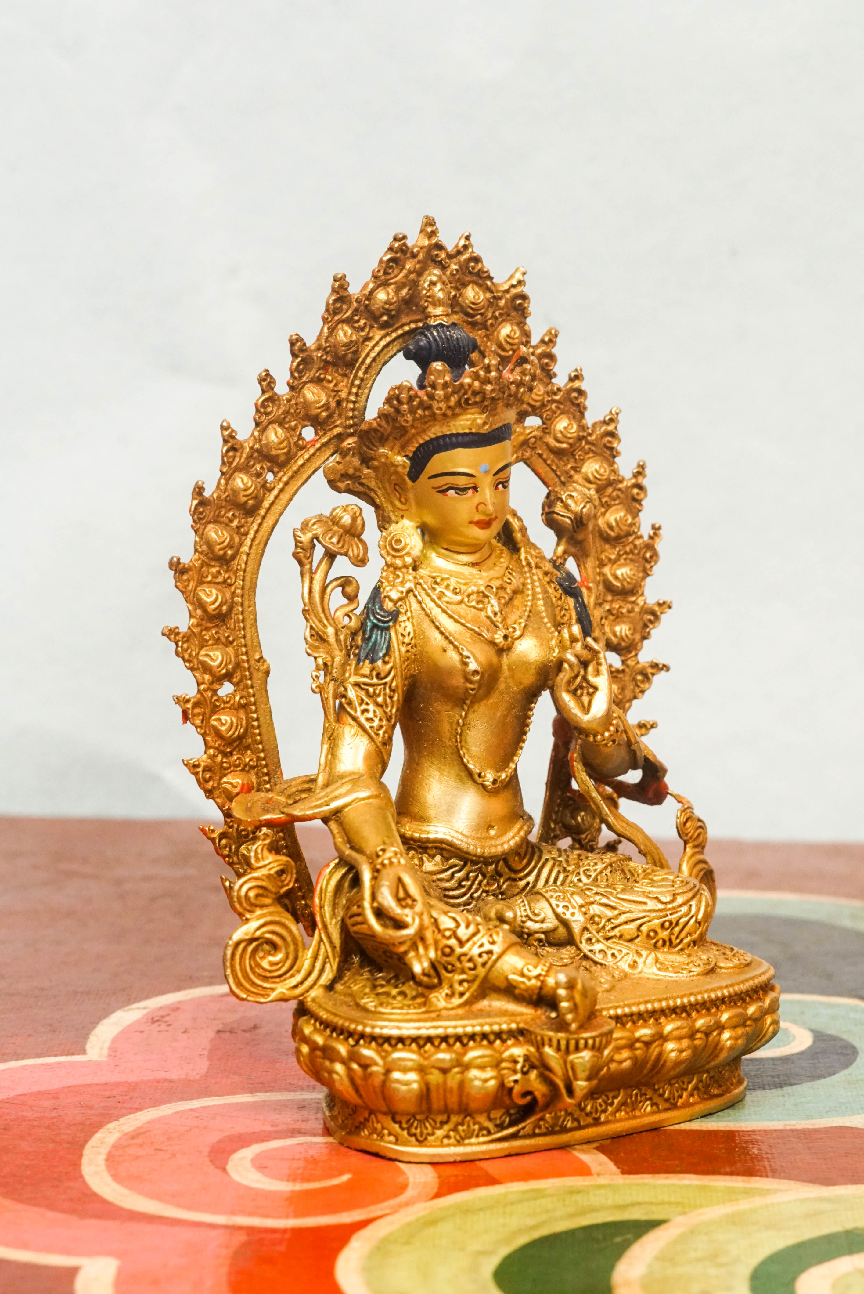 Gold-plated Green Tara statue with flaming halo, symbolizing compassion, protection, and spiritual transformation.