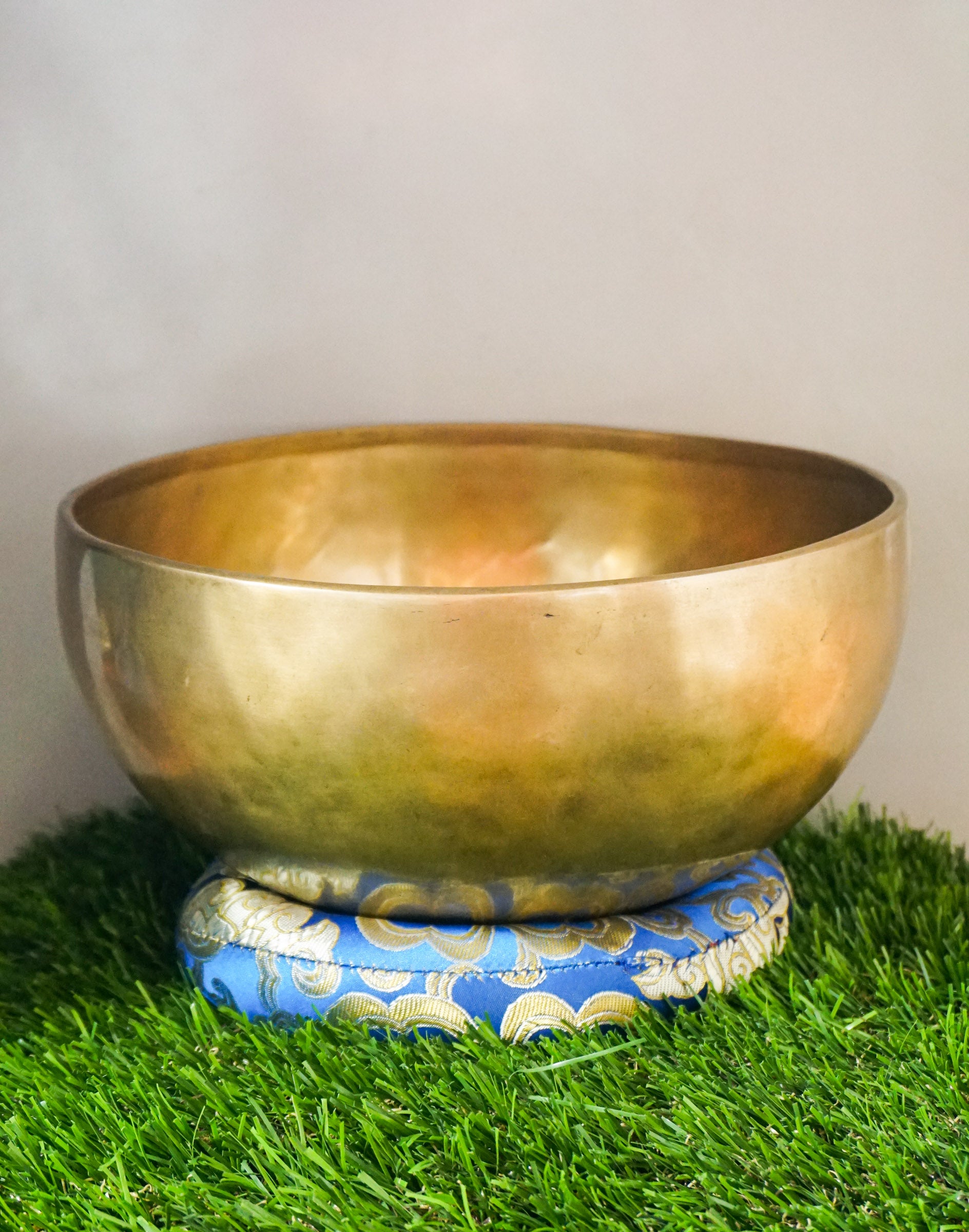 Handmade brass Tibetan singing bowl on a red cushion for sound healing.