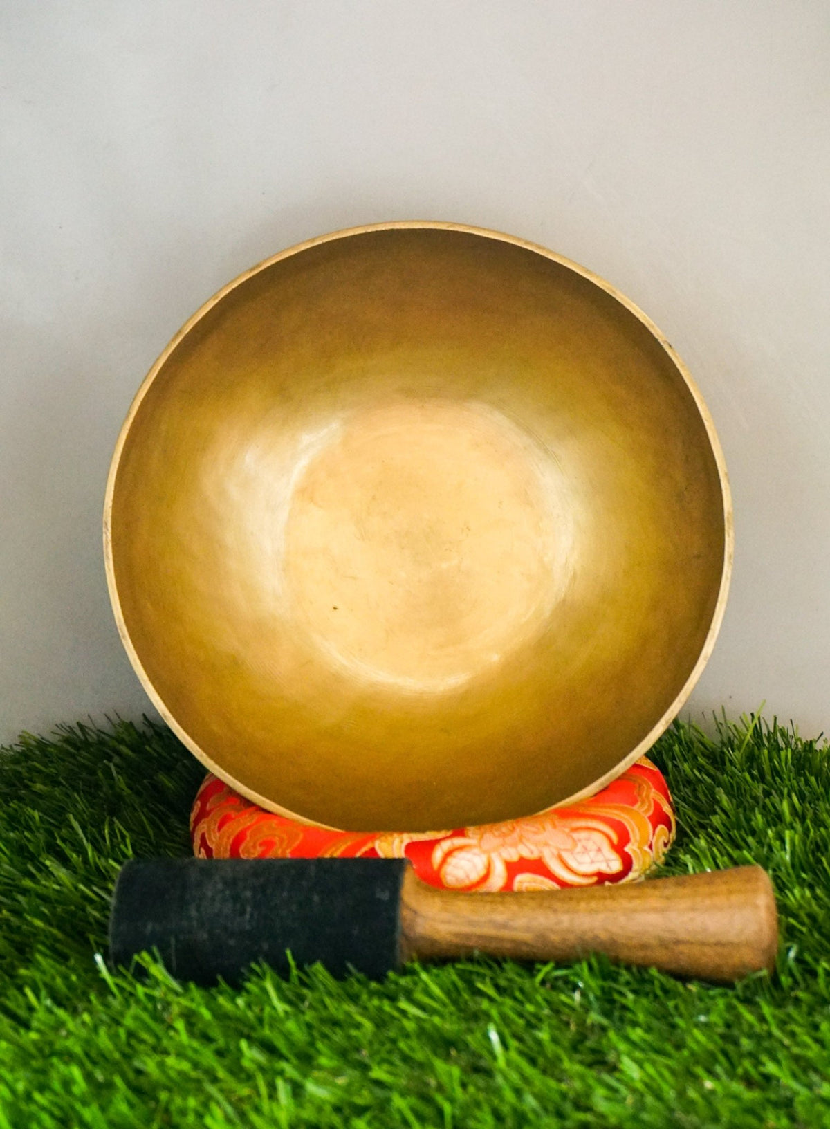 Handmade brass Tibetan singing bowl on a red cushion for sound healing.