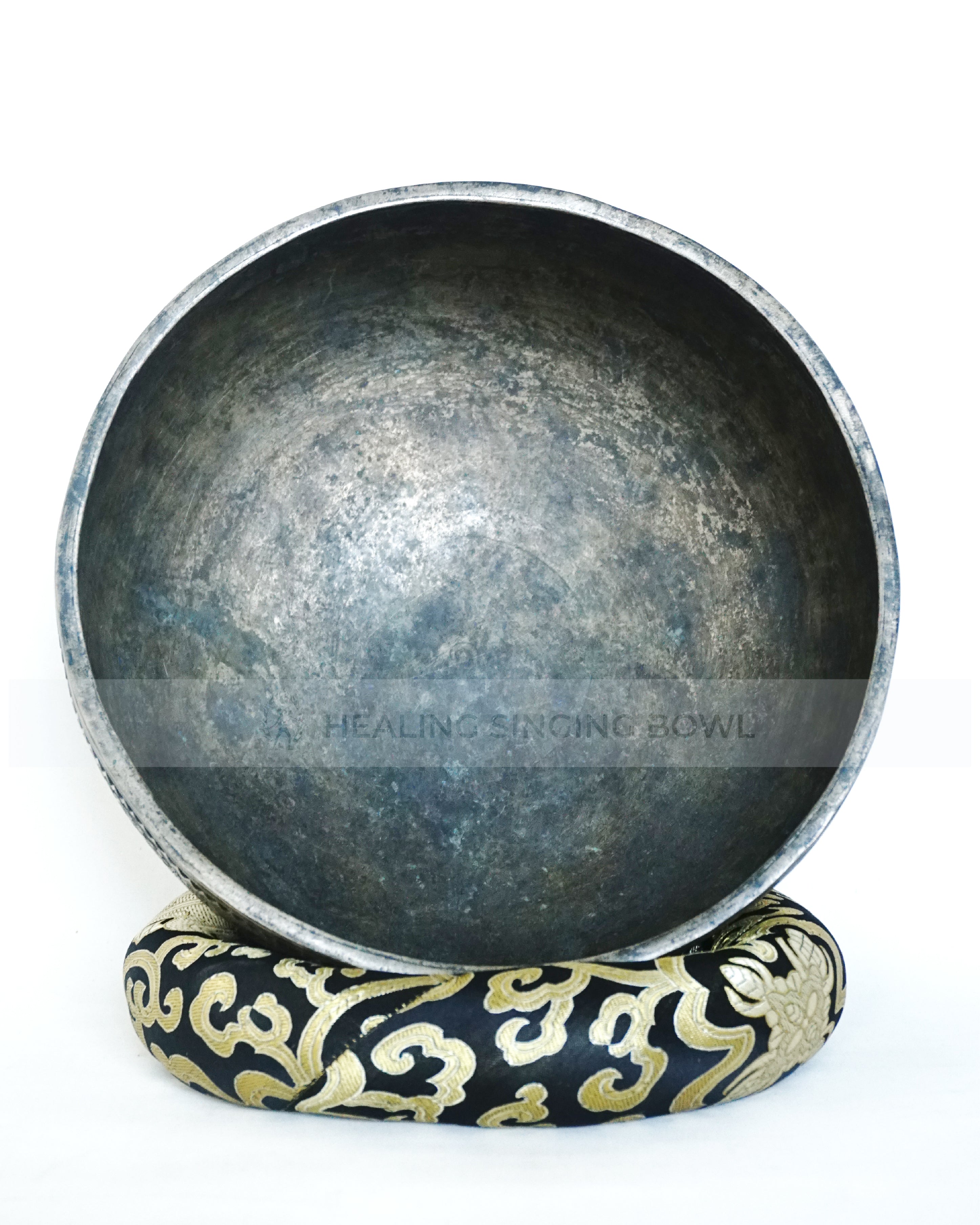 Large hand-hammered Tibetan singing bowl with a 24.5 cm diameter, shown from the top view and placed on a decorative cushion against a white background.