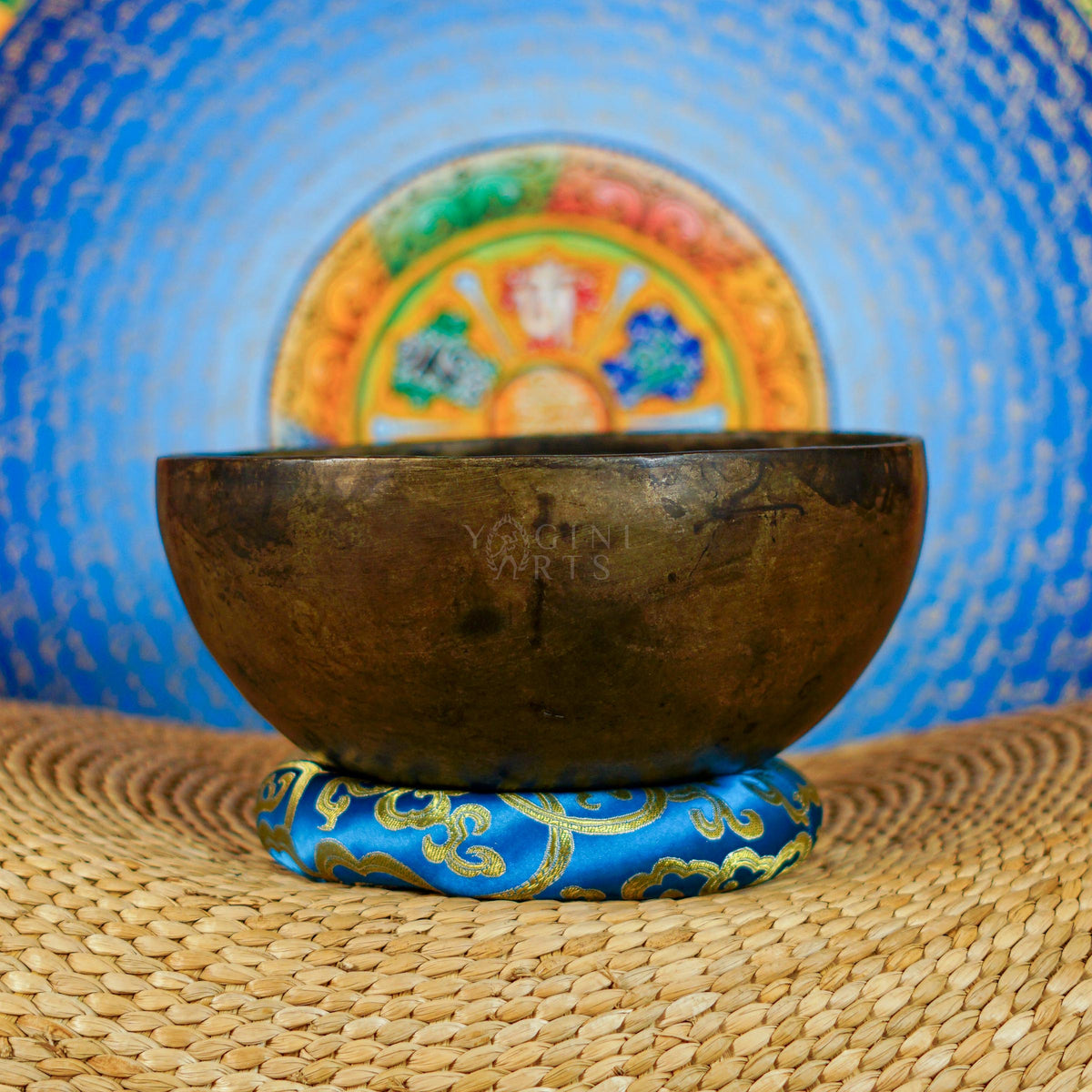 Semi antique Tibetan singing bowl handmade in Nepal with aged bronze finish on a traditional blue cushion