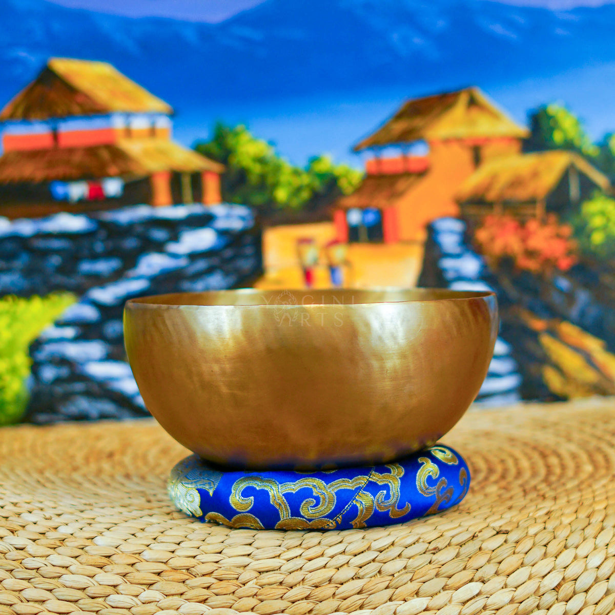 Handcrafted Himalayan singing bowl with a warm bronze-gold finish displayed on a decorative blue cushion for meditation practice.