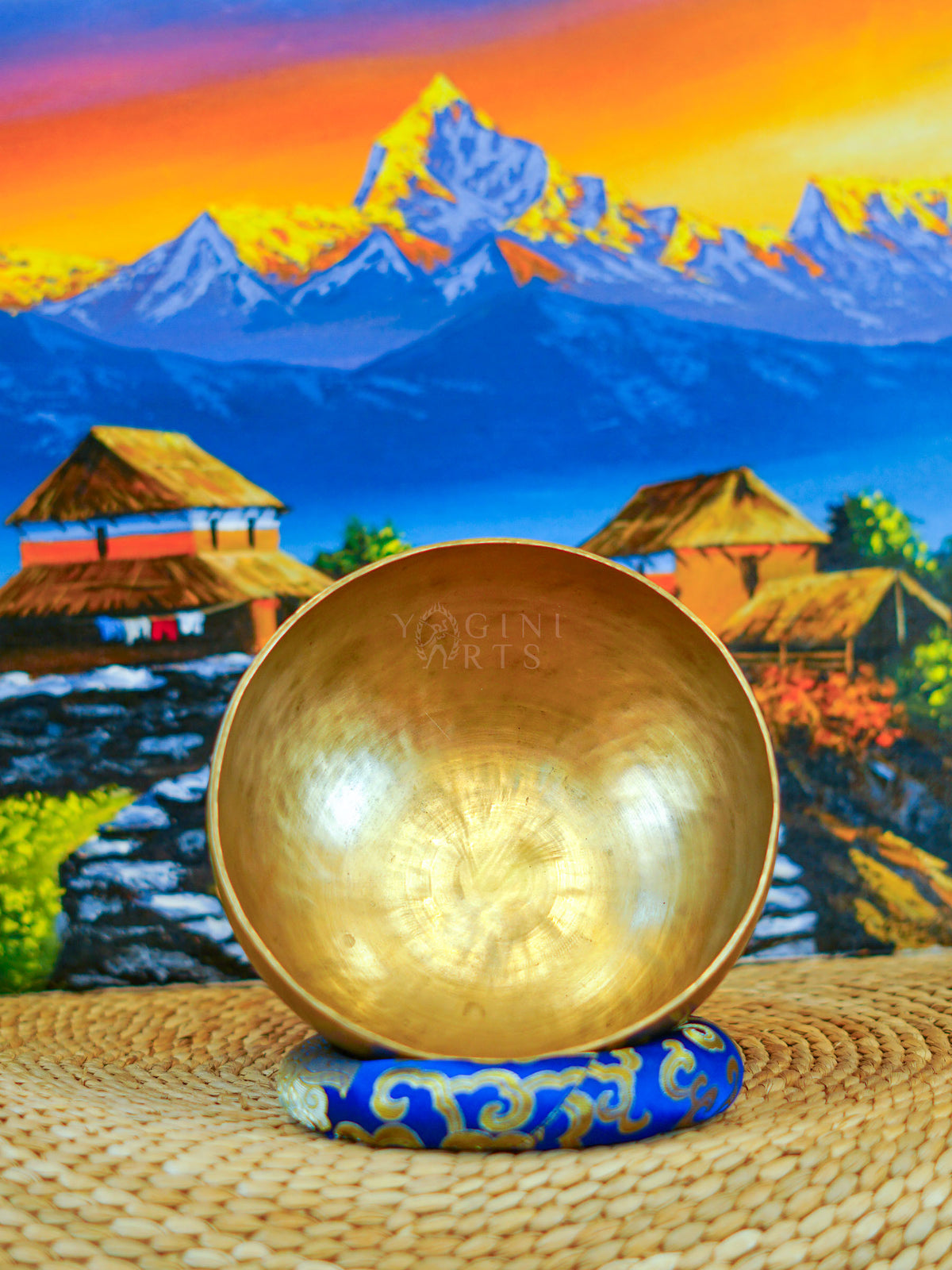 Front view of a handmade bronze-gold singing bowl showing its smooth metal surface and rounded form on a patterned cushion.