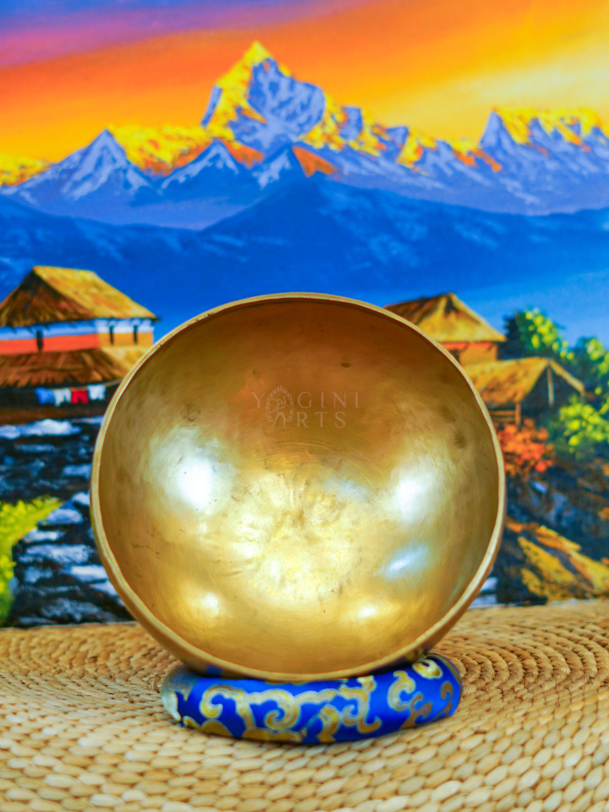 Front view of a handmade bronze-gold singing bowl showing its smooth metal surface and rounded form on a patterned cushion.