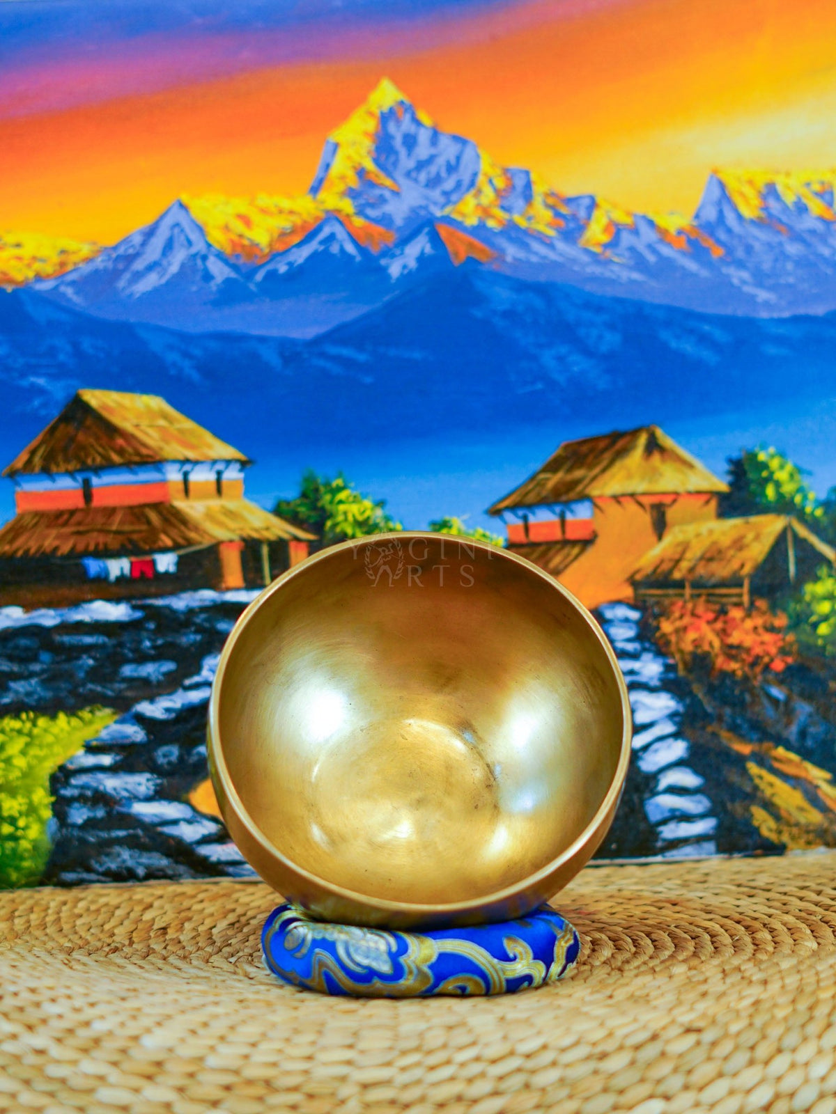 Front view of a handmade bronze-gold singing bowl showing its smooth metal surface and rounded form on a patterned cushion.