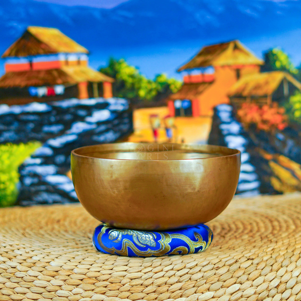 Handcrafted Himalayan singing bowl with a warm bronze-gold finish displayed on a decorative blue cushion for meditation practice.
