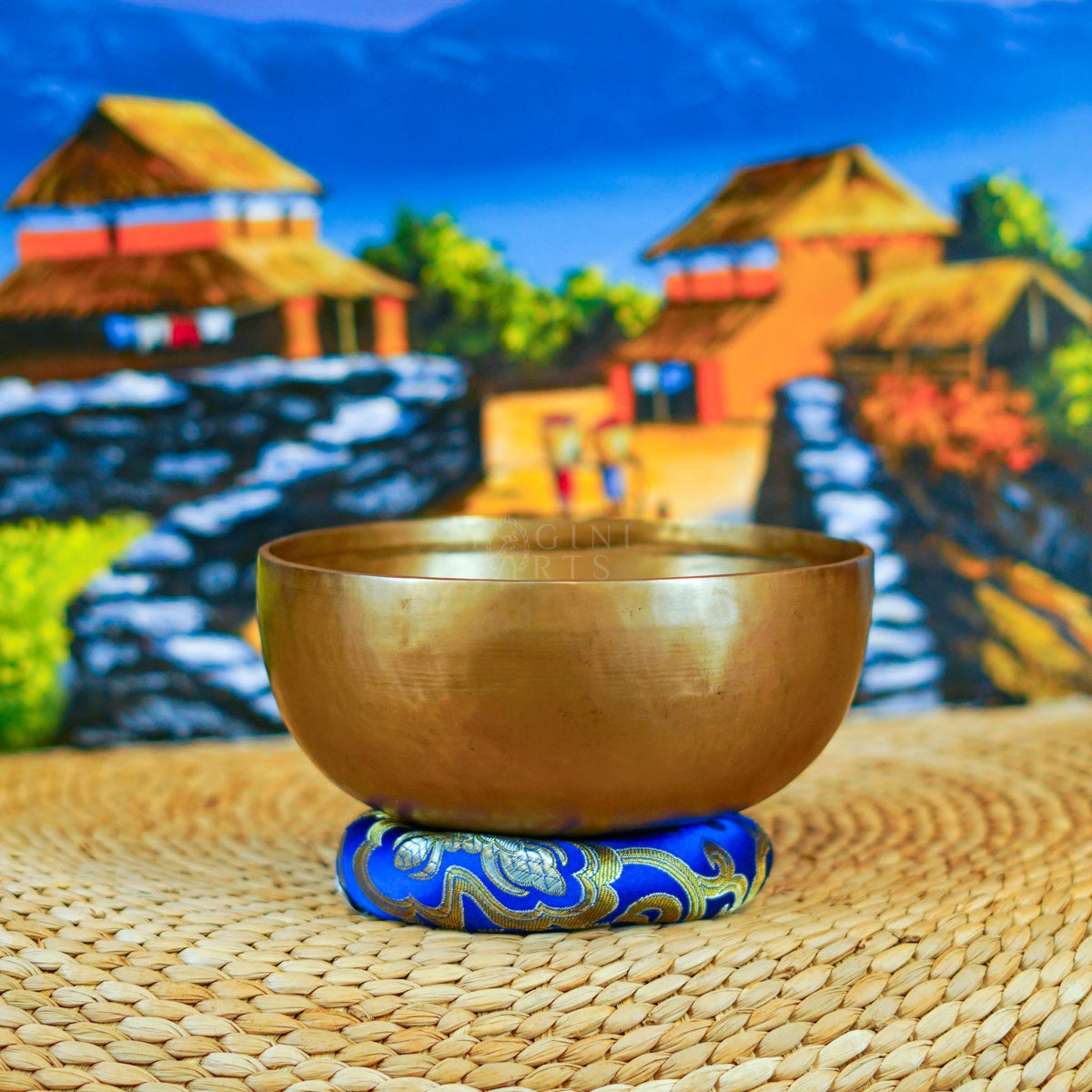 Handcrafted Himalayan singing bowl with a warm bronze-gold finish displayed on a decorative blue cushion for meditation practice.