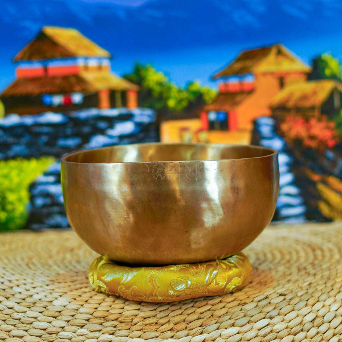 Side view of a handmade Himalayan singing bowl with a smooth bronze-gold finish displayed on a decorative yellow cushion.