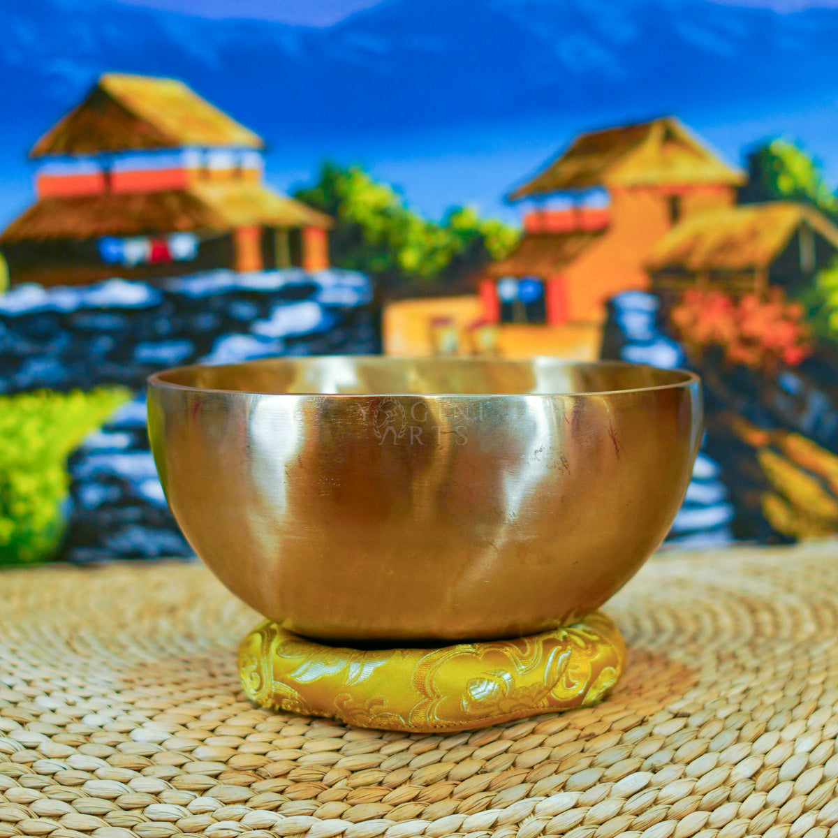 Side view of a handmade Himalayan singing bowl with a smooth bronze-gold finish displayed on a decorative yellow cushion.