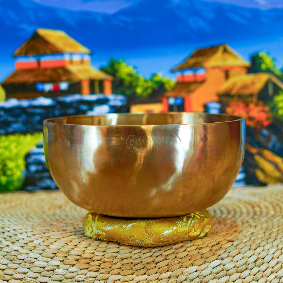 Side view of a handmade Himalayan singing bowl with a smooth bronze-gold finish displayed on a decorative yellow cushion.