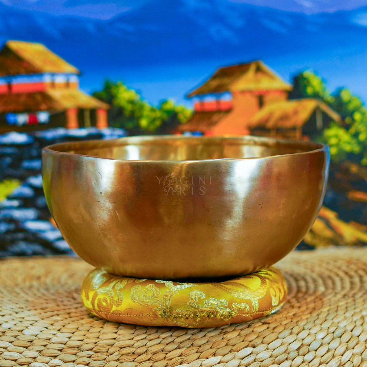 Side view of a handmade Himalayan singing bowl with a smooth bronze-gold finish displayed on a decorative yellow cushion.