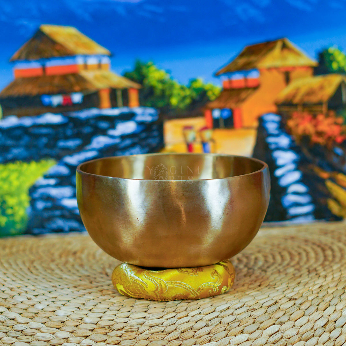 Side view of a handmade Himalayan singing bowl with a smooth bronze-gold finish displayed on a decorative yellow cushion.