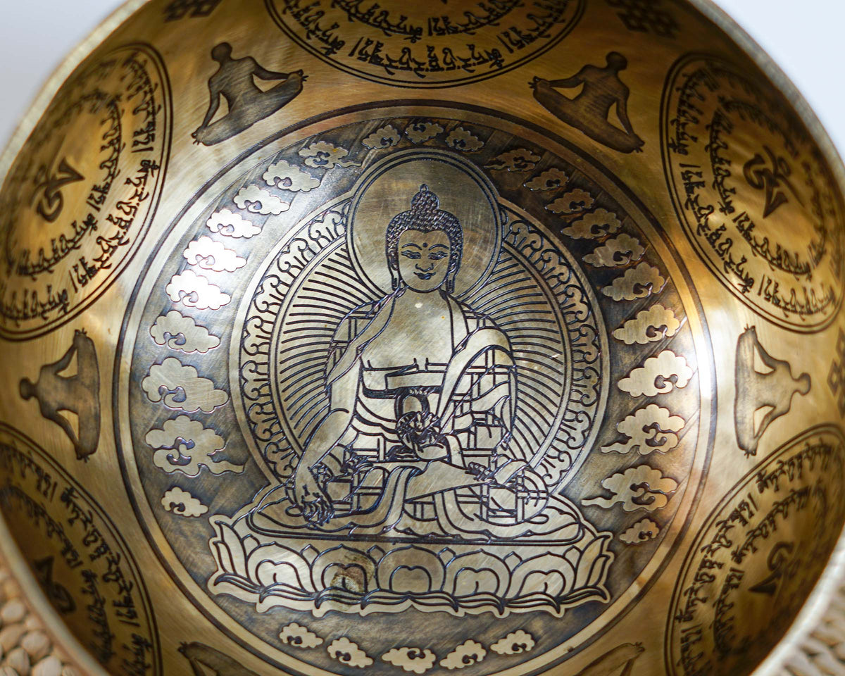 Close up of Medicine Buddha engraving surrounded by traditional Tibetan Buddhist symbols inside the singing bowl