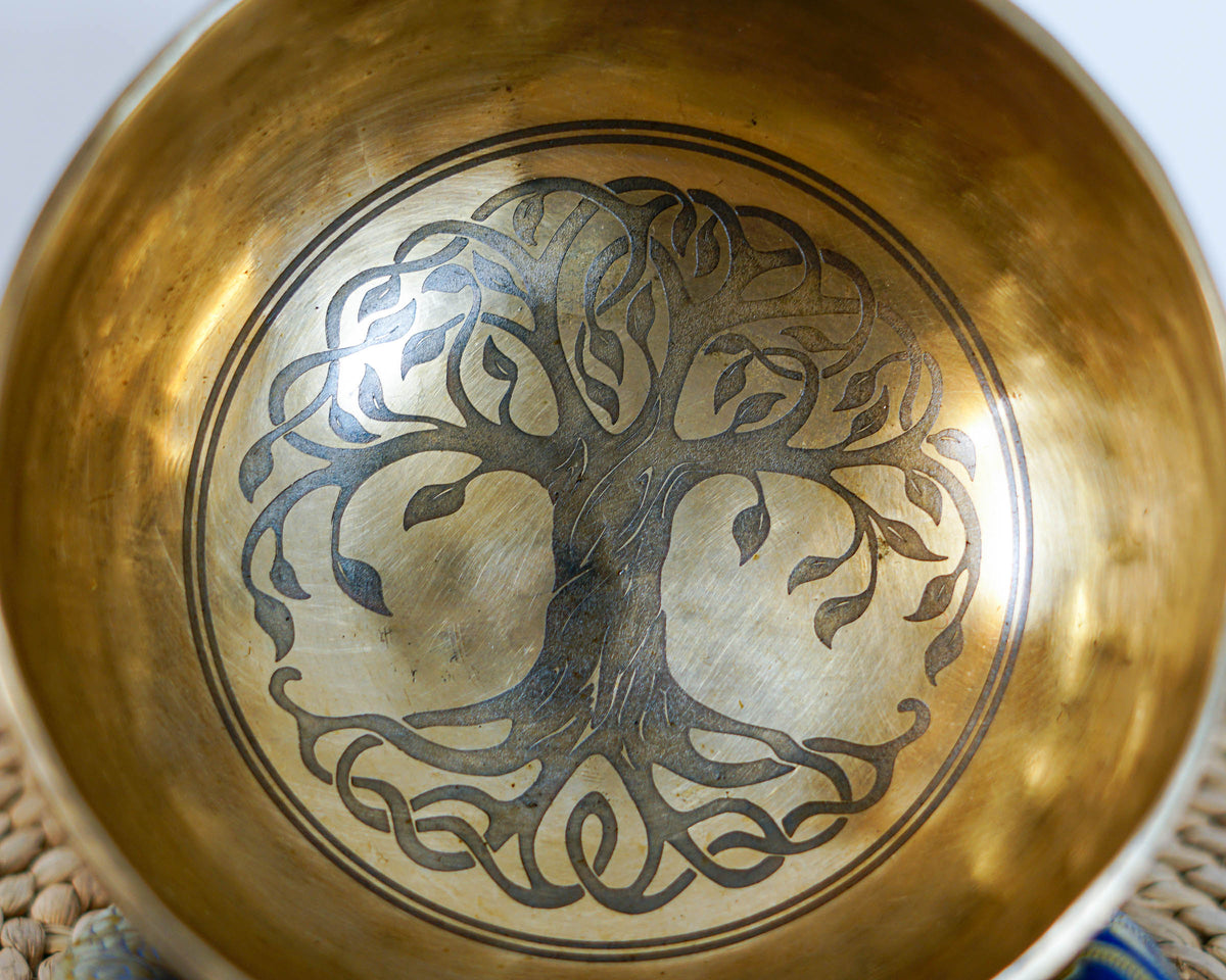 Close up of Tree of Life engraving inside a golden singing bowl showing detailed branches, leaves, and roots.