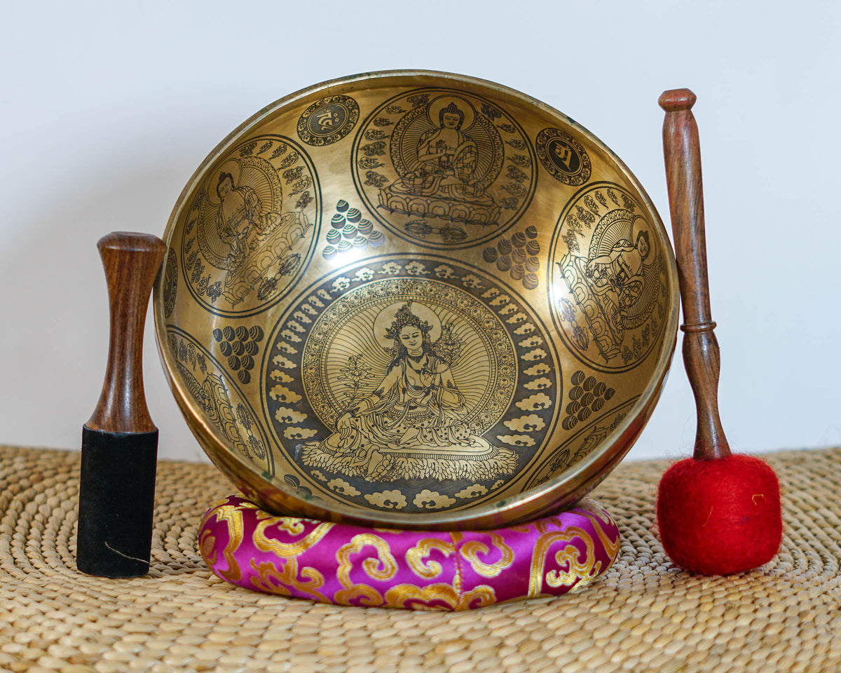 Green Tara singing bowl showing engraved dragons, auspicious knots, and traditional Himalayan decorative motifs on the exterior