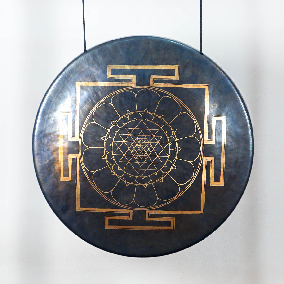 Close-up of a dark metallic gong showing its detailed gold Sri Yantra-inspired geometric mandala and lotus-petal design.