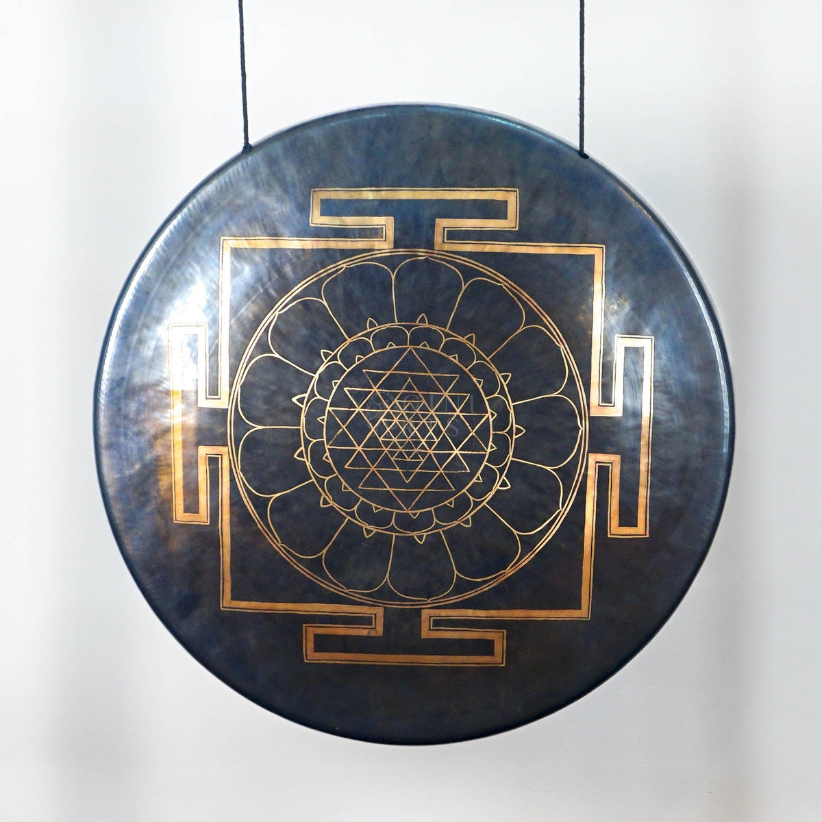Close-up of a dark metallic gong showing its detailed gold Sri Yantra-inspired geometric mandala and lotus-petal design.