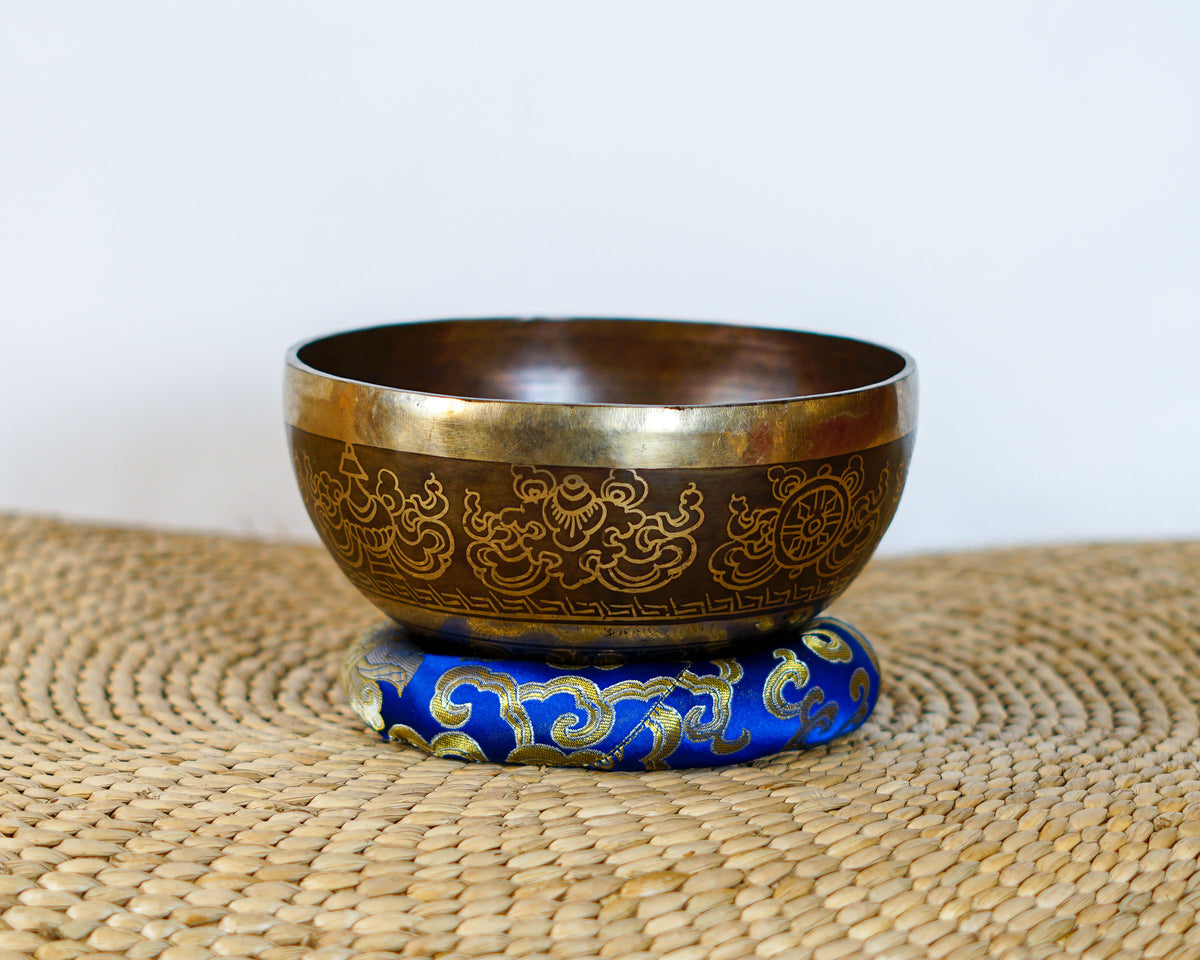Flower of Life engraved Tibetan singing bowl with a dark bronze exterior and intricate decorative motifs.