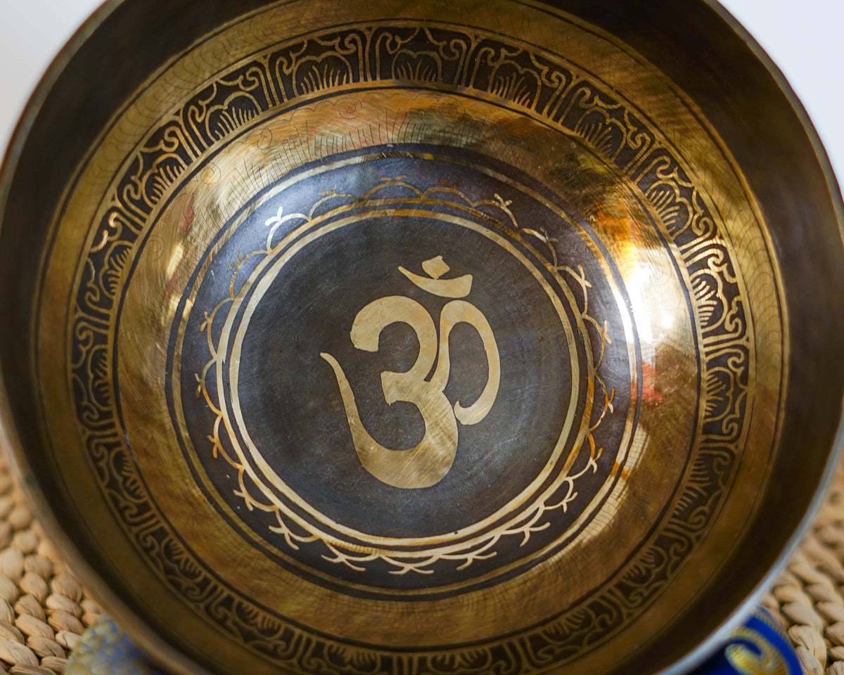 Close up of a golden Om symbol engraved inside a dark circular center of a Hindu singing bowl.