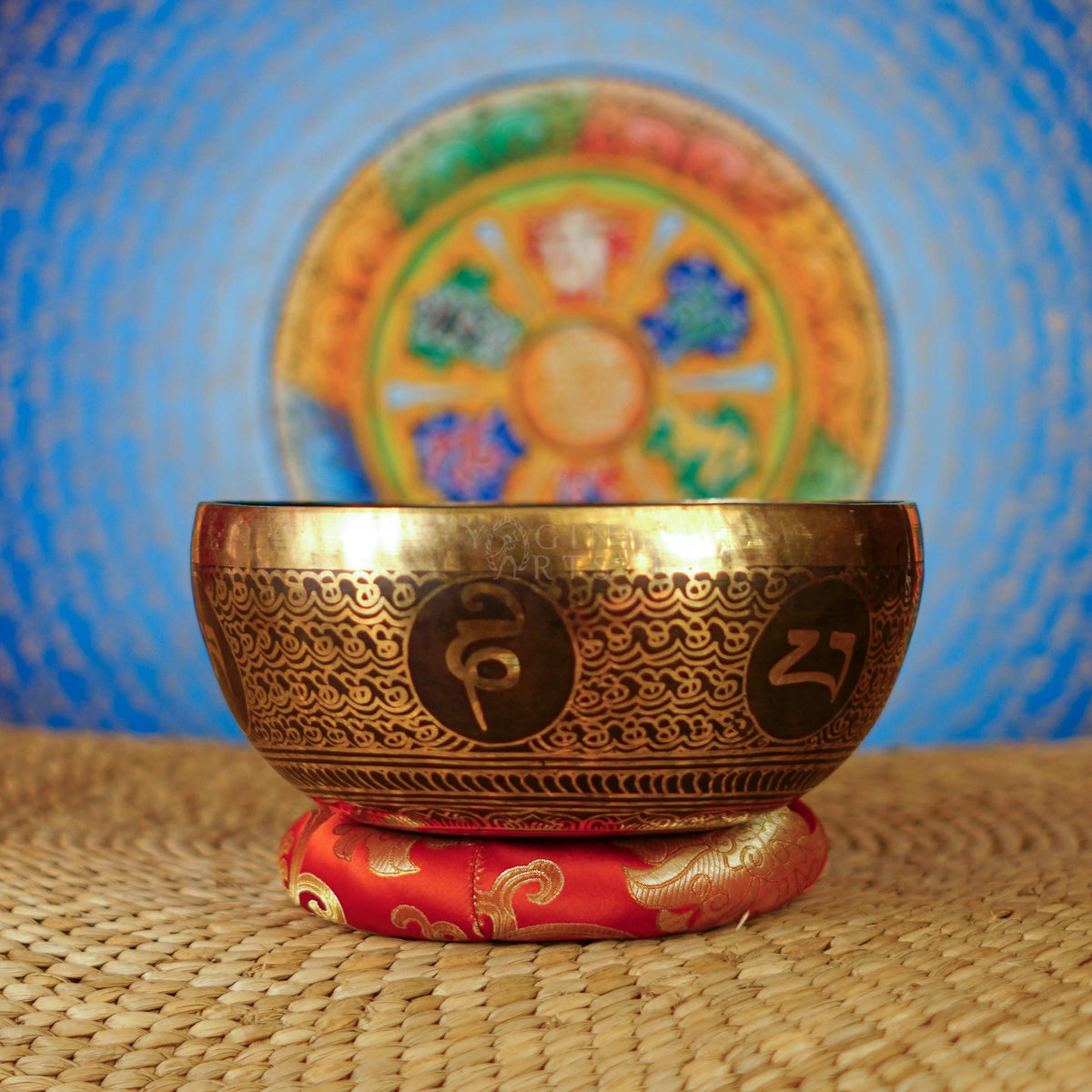 Handcrafted Tibetan singing bowl from Nepal with Buddhist symbol engraving, Tibetan-style script, bronze-gold finish, red cushion and wooden striker.