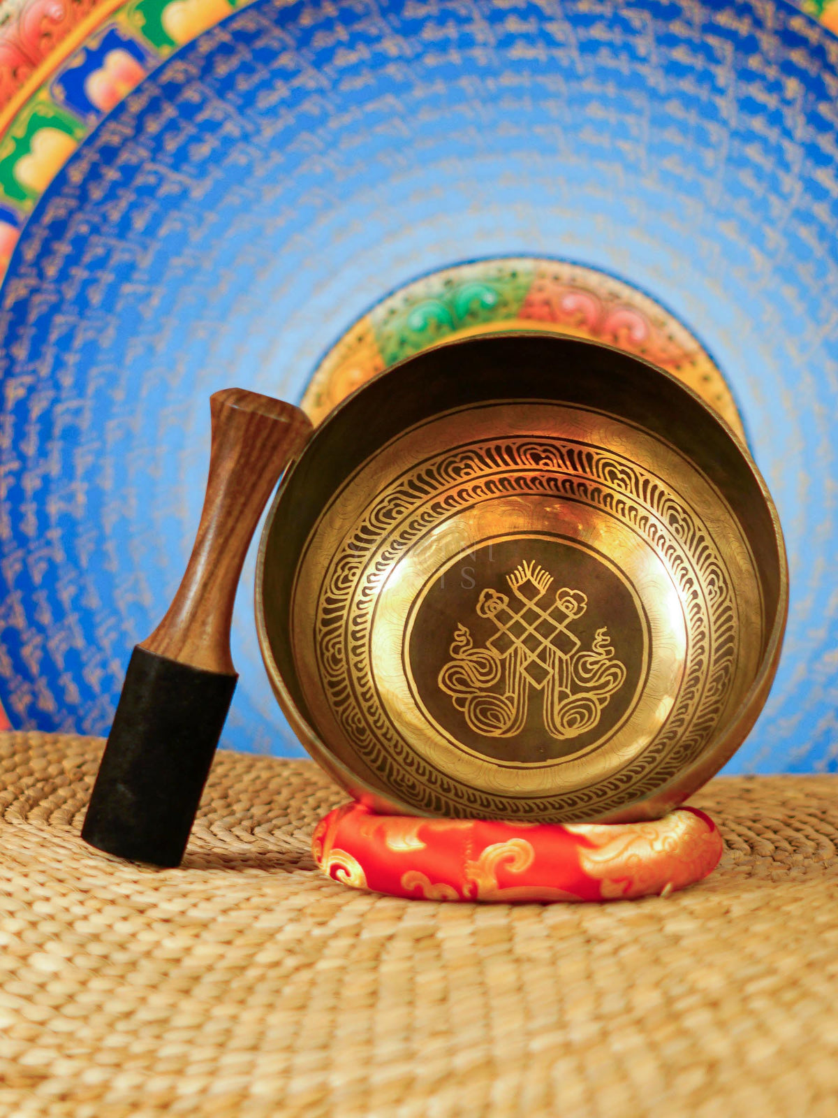Handcrafted Tibetan singing bowl from Nepal with Buddhist symbol engraving, Tibetan-style script, bronze-gold finish, red cushion and wooden striker.