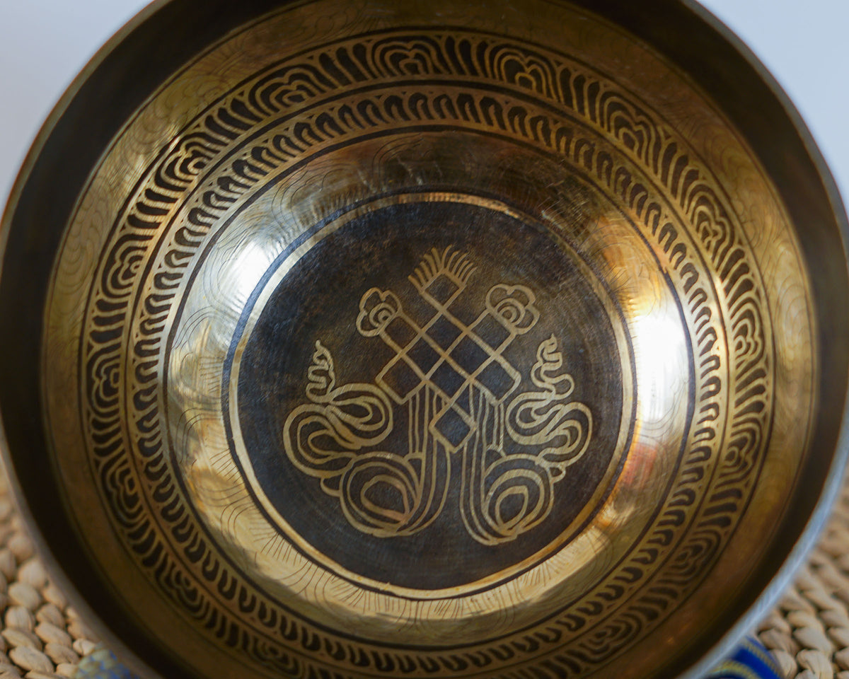 Close up of the Endless Knot engraving inside a golden Tibetan singing bowl with decorative antique finish.