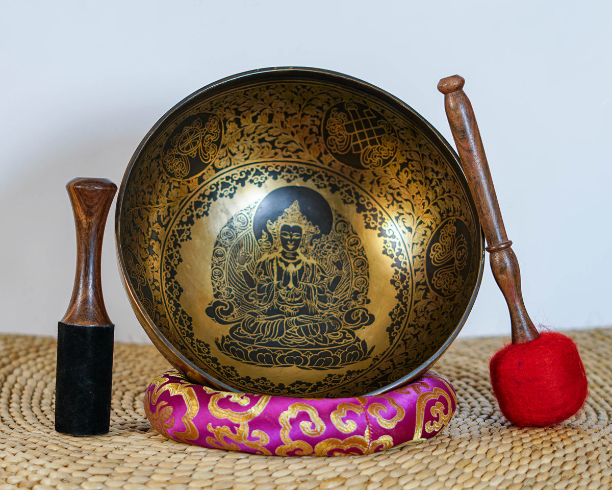 Chengresi engraved singing bowl displayed upright with a wooden striker, red felt mallet, and decorative brocade cushion.