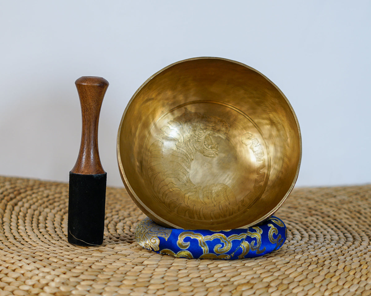 Close up of a detailed hand-engraved tiger motif with fine stippling inside a golden bronze Tibetan singing bowl.