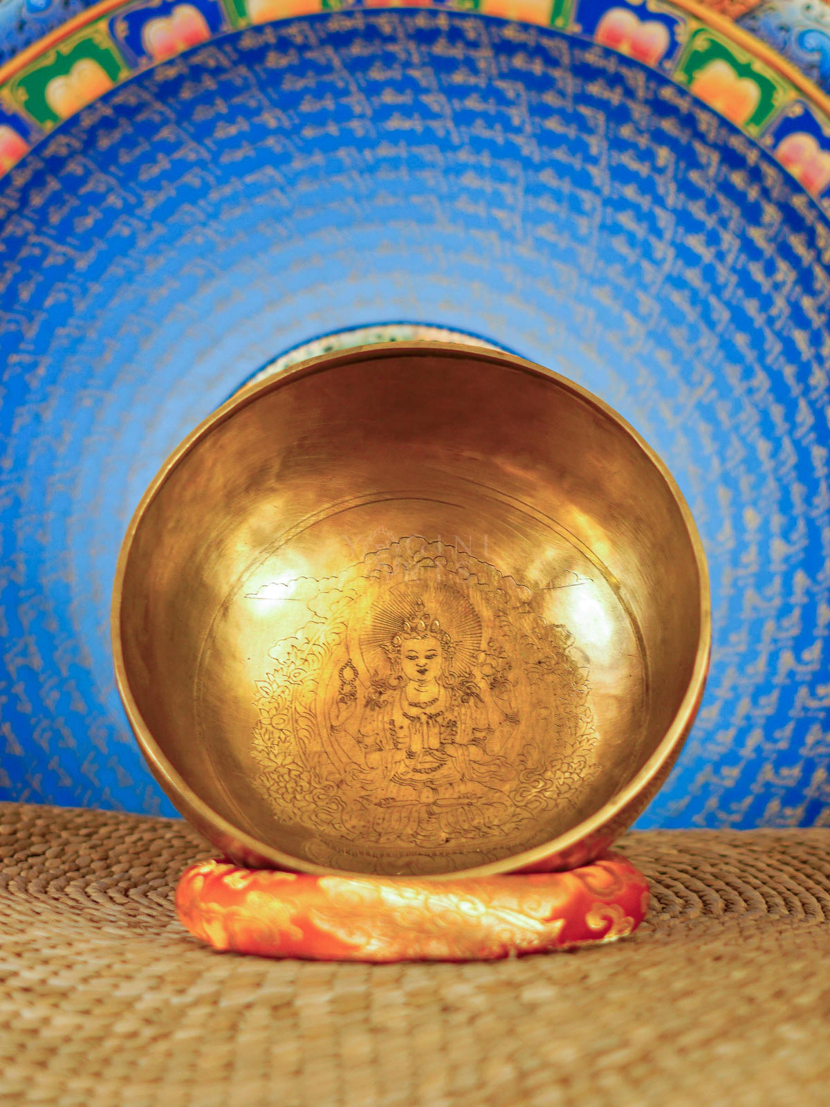 Chengresi Tibetan singing bowl with engraved Buddhist design on red cushion