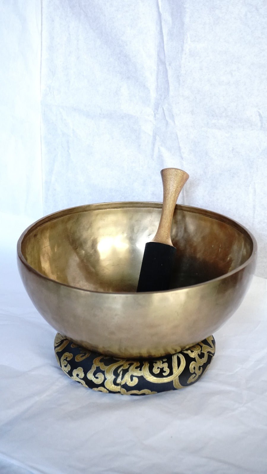 Handcrafted Tibetan brass singing bowl with wooden striker on brocade cushion
