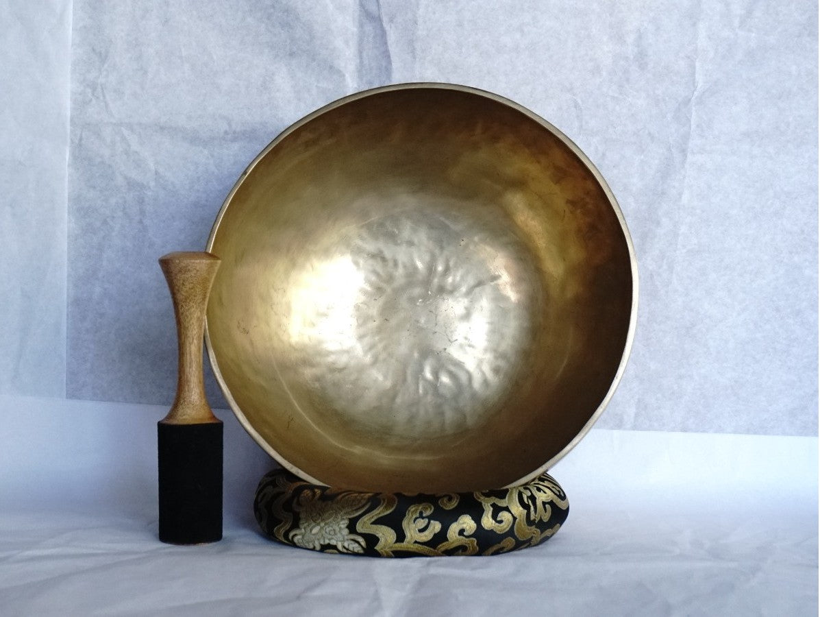 Handcrafted Tibetan brass singing bowl with wooden striker on brocade cushion