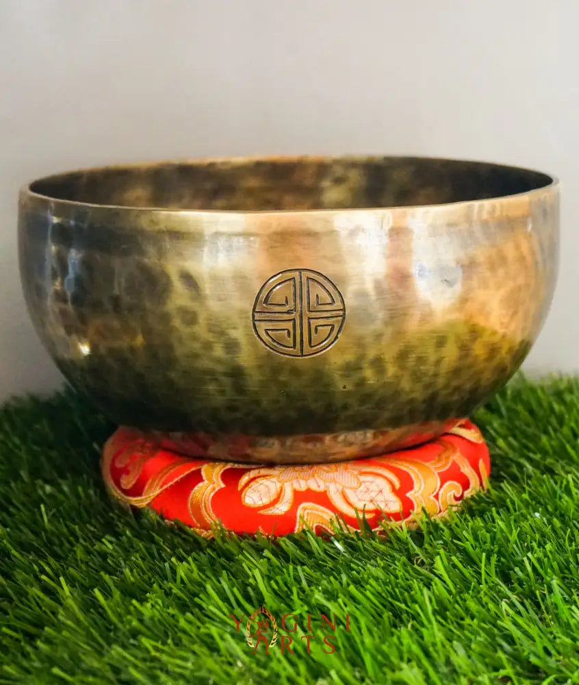 Bronze singing bowl with a red and gold base on grass