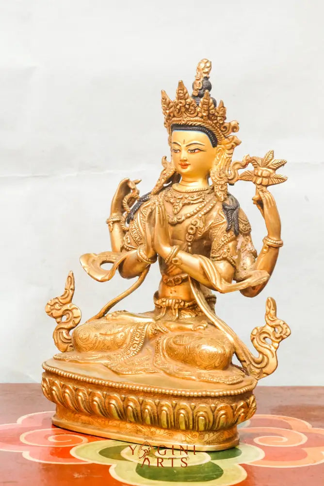 Gold-plated statue of Chengresi (Chenrezig), the Tibetan Buddhist deity of compassion, depicted with four arms in a meditative posture, adorned with ornate jewelry and a serene facial expression.