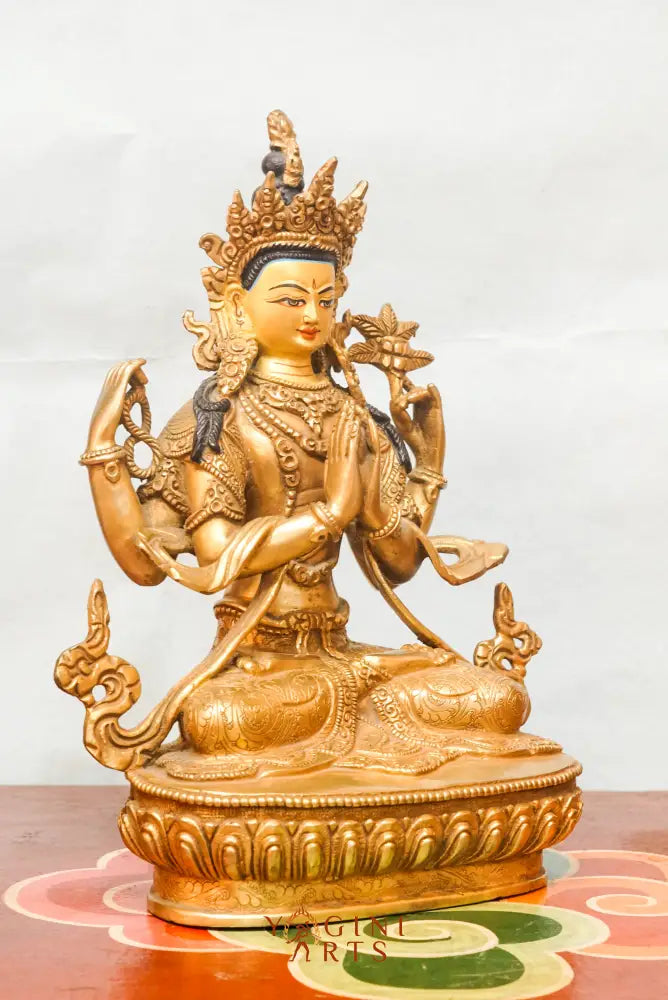 Gold-plated statue of Chengresi (Chenrezig), the Tibetan Buddhist deity of compassion, depicted with four arms in a meditative posture, adorned with ornate jewelry and a serene facial expression.