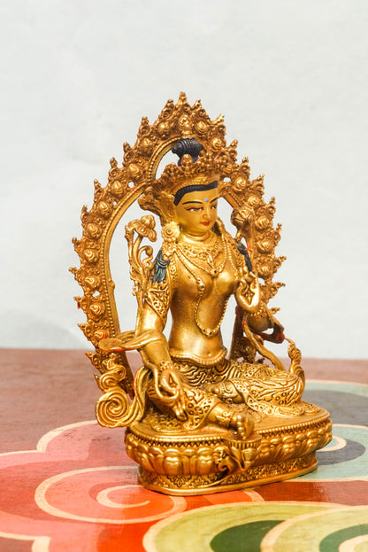 Gold-plated Green Tara statue with flaming halo, symbolizing compassion, protection, and spiritual transformation.