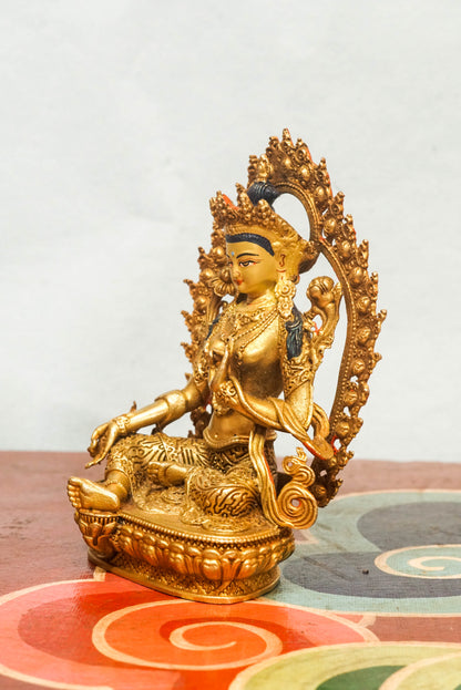 Gold-plated Green Tara statue with flaming halo, symbolizing compassion, protection, and spiritual transformation.