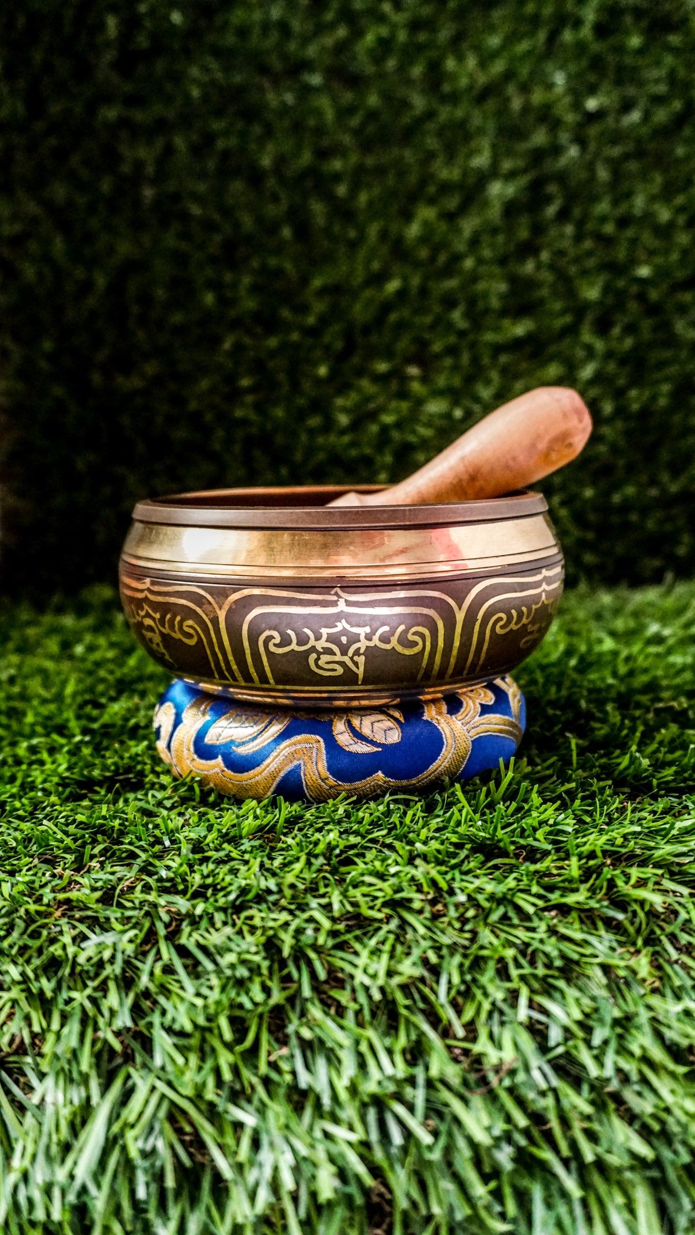 Singing bowl with a carved meditating Buddha inside and "Om Mani Padme Hum" mantra in a floral design on the outside.
