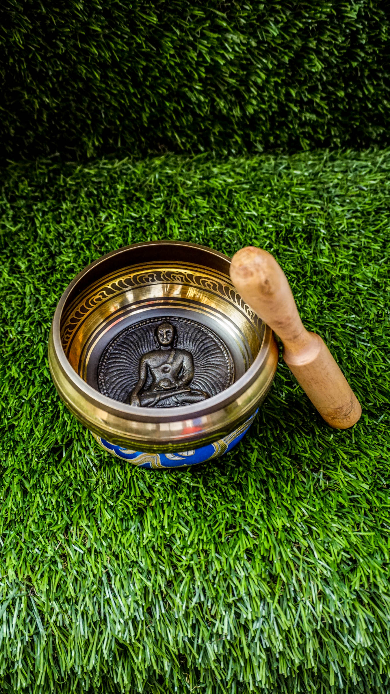 Singing bowl with a carved meditating Buddha inside and "Om Mani Padme Hum" mantra in a floral design on the outside.