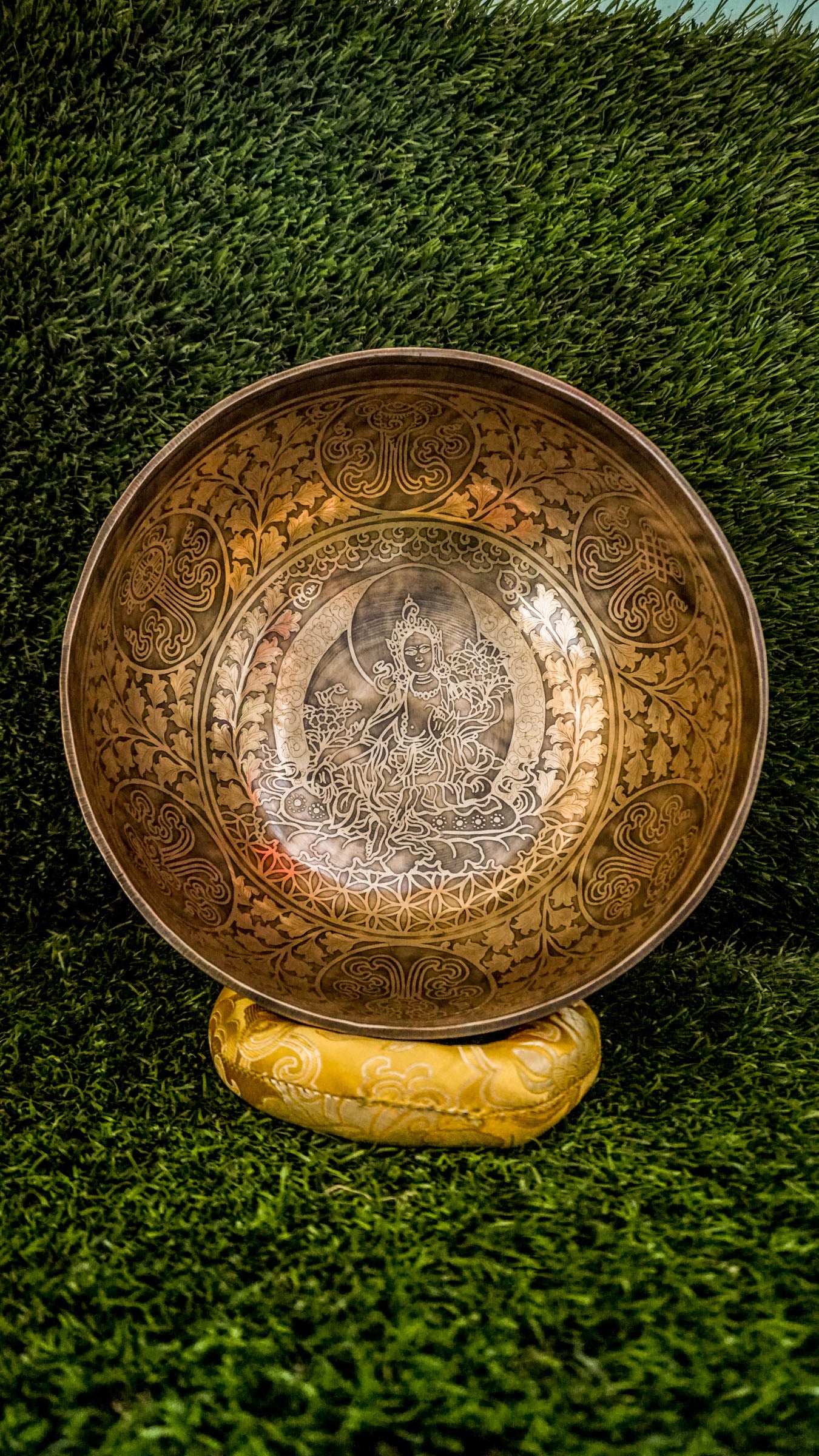 Invite compassion and healing into your space with our handcrafted Green Tara Singing Bowl. Featuring a detailed image of Green Tara inside, it symbolizes protection, care, and swift aid. The exterior is engraved with sacred patterns that amplify her blessings. Handmade by skilled artisans, this bowl produces clear, soothing tones that promote peace and focus. Includes a wooden mallet and silk cushion for easy use and care.