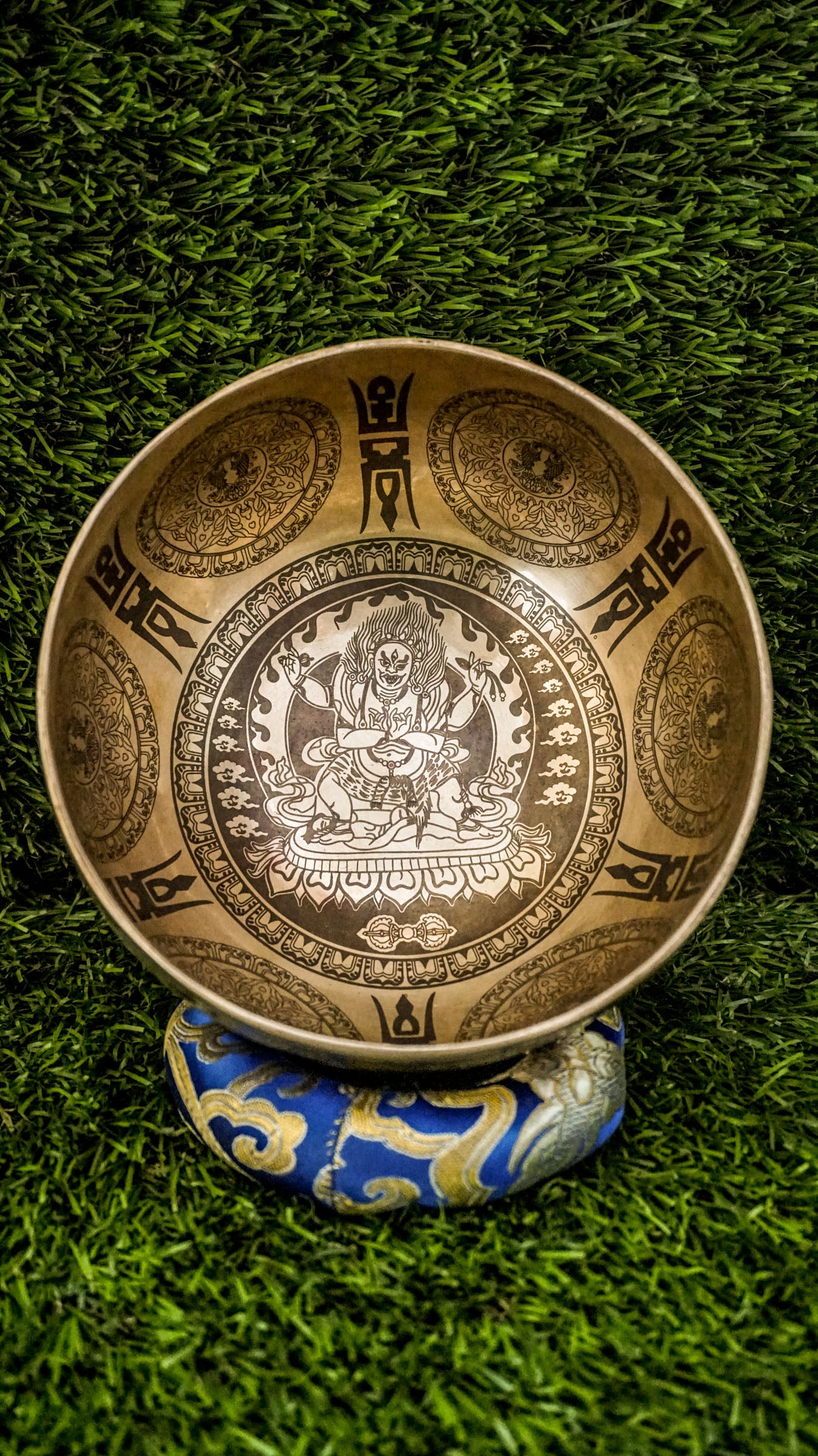 Invite protection, strength, and transformation with our handcrafted Mahakala Singing Bowl. Featuring a finely engraved image of Mahakala inside, it symbolizes fearless guardianship and obstacle removal. The exterior is adorned with protective motifs to deepen its sacred energy. Handmade by skilled artisans, this bowl produces deep, grounding tones that support meditation and spiritual empowerment. Includes a wooden mallet and silk cushion for easy use and care.