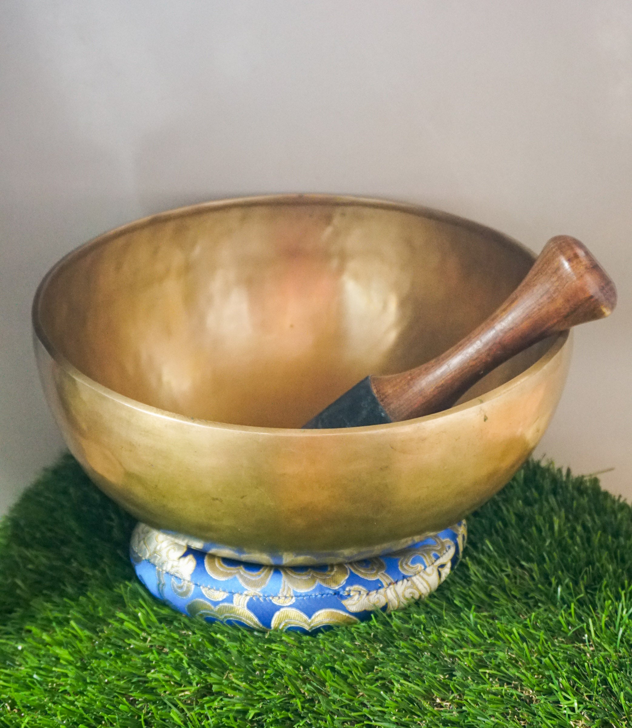 Handmade brass Tibetan singing bowl on a red cushion for sound healing.