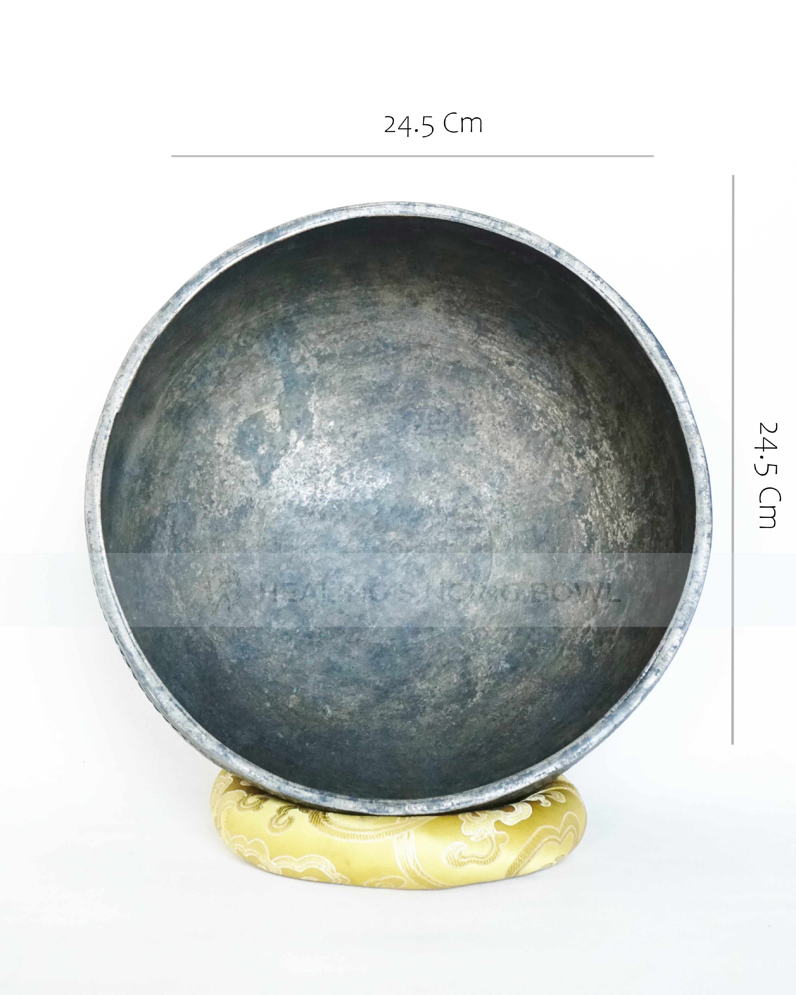 Large hand-hammered Tibetan singing bowl with a 24.5 cm diameter, shown from the top view and placed on a decorative cushion against a white background.