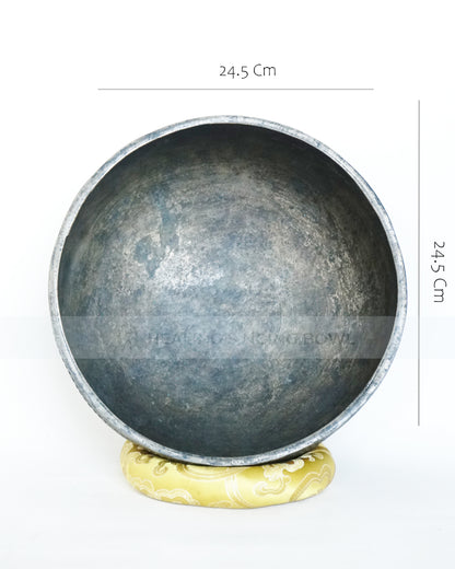 Large hand-hammered Tibetan singing bowl with a 24.5 cm diameter, shown from the top view and placed on a decorative cushion against a white background.