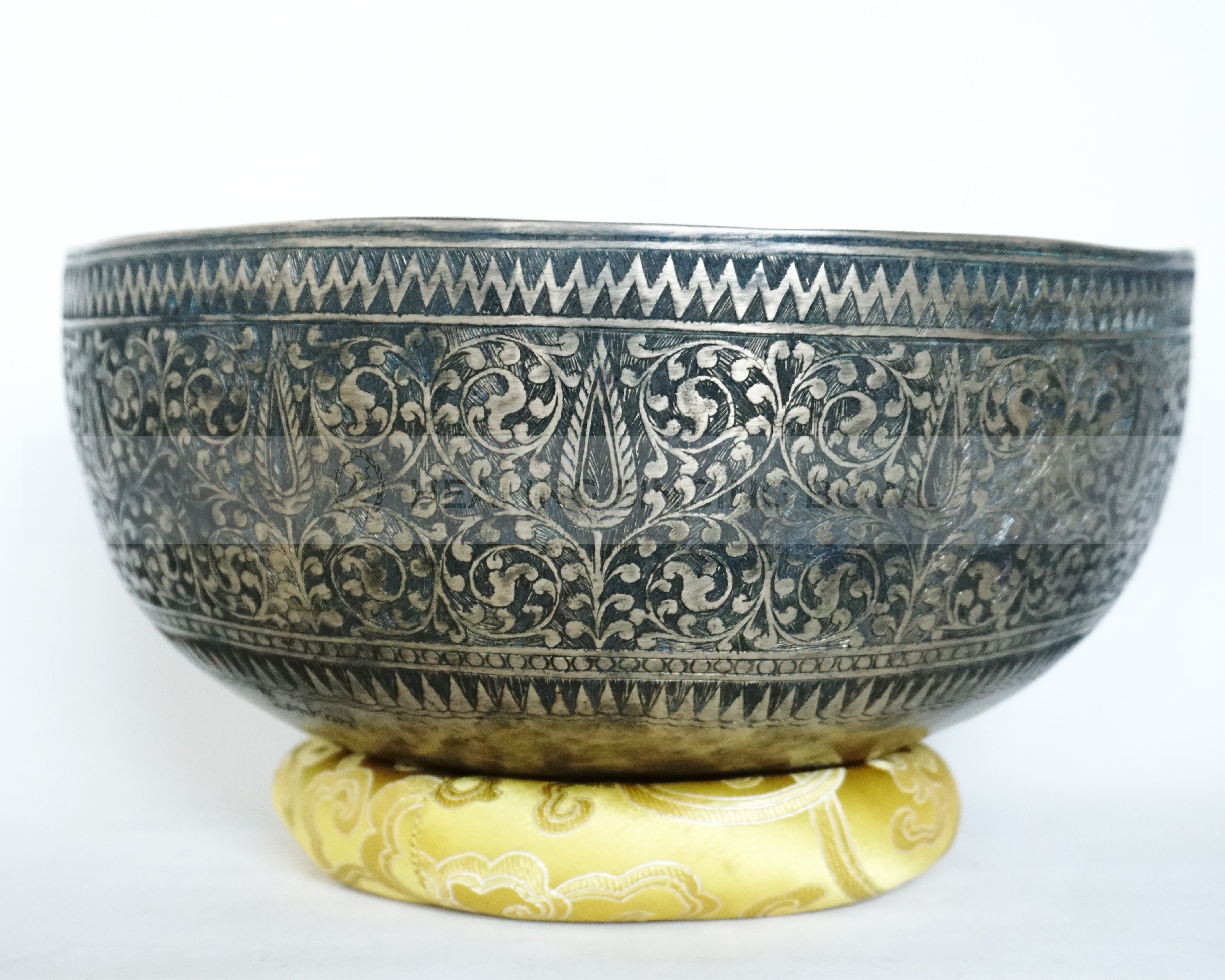 Large hand-hammered Tibetan singing bowl with a 24.5 cm diameter, shown from the top view and placed on a decorative cushion against a white background.