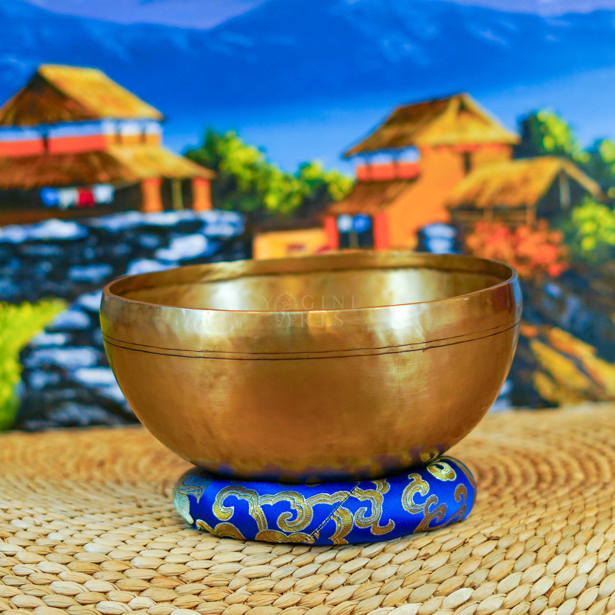 Handcrafted Himalayan singing bowl with a warm bronze-gold finish displayed on a decorative blue cushion for meditation practice.