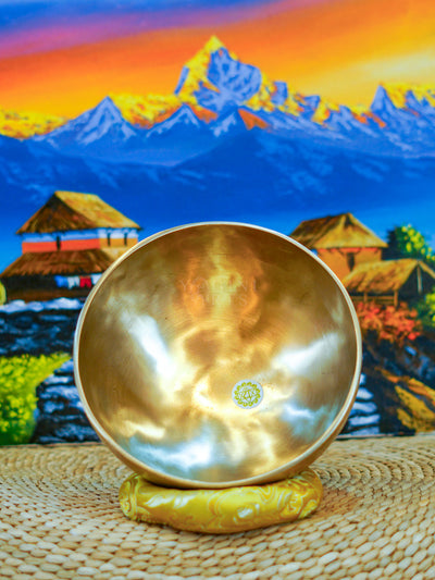 Seven handcrafted Himalayan singing bowls arranged together, showing graduated sizes, chakra symbols, and warm antique bronze-gold finishes.