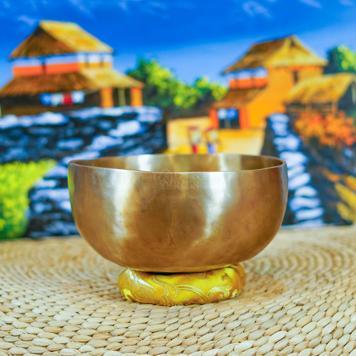 Side view of a handmade Himalayan singing bowl with a smooth bronze-gold finish displayed on a decorative yellow cushion.