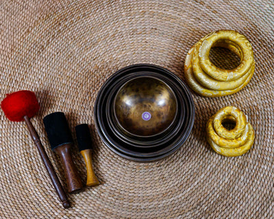 Seven handcrafted chakra singing bowls arranged together, showing different sizes, warm antique metallic finishes and individual chakra symbols.