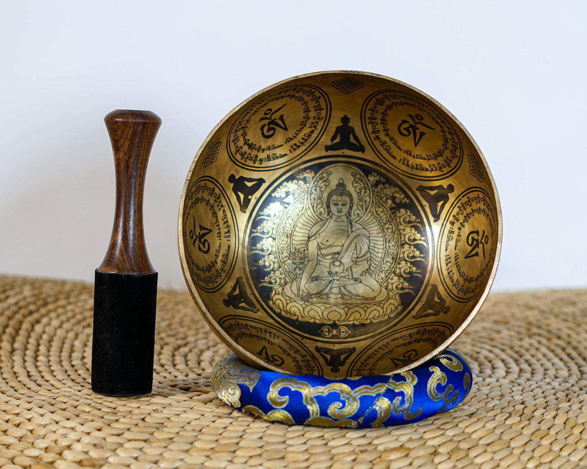 Golden Medicine Buddha singing bowl displayed on a blue brocade cushion
